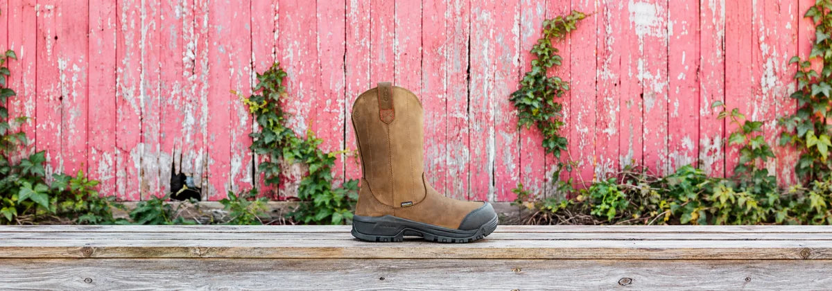 Women's KEEN Utility Evanston pull-on work boot in Bison and Black against a pink wooden wall